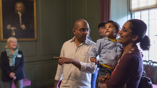 A family with a young child admiring the collections, with a tour guide in the background at Treasurer's House in Yorkshire.